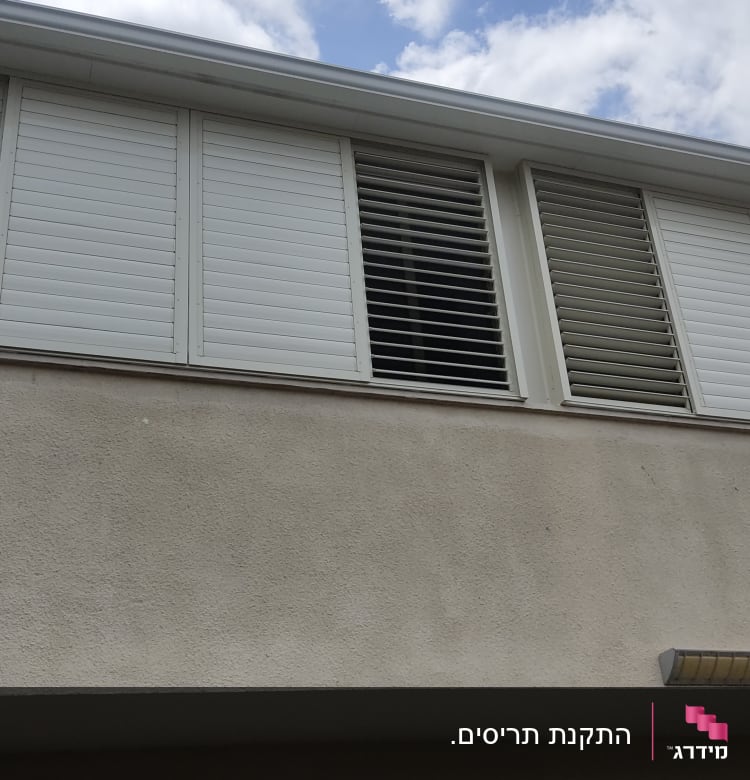 תריסים לבנים סגורים וחלקם פתוחים בחלון עליון